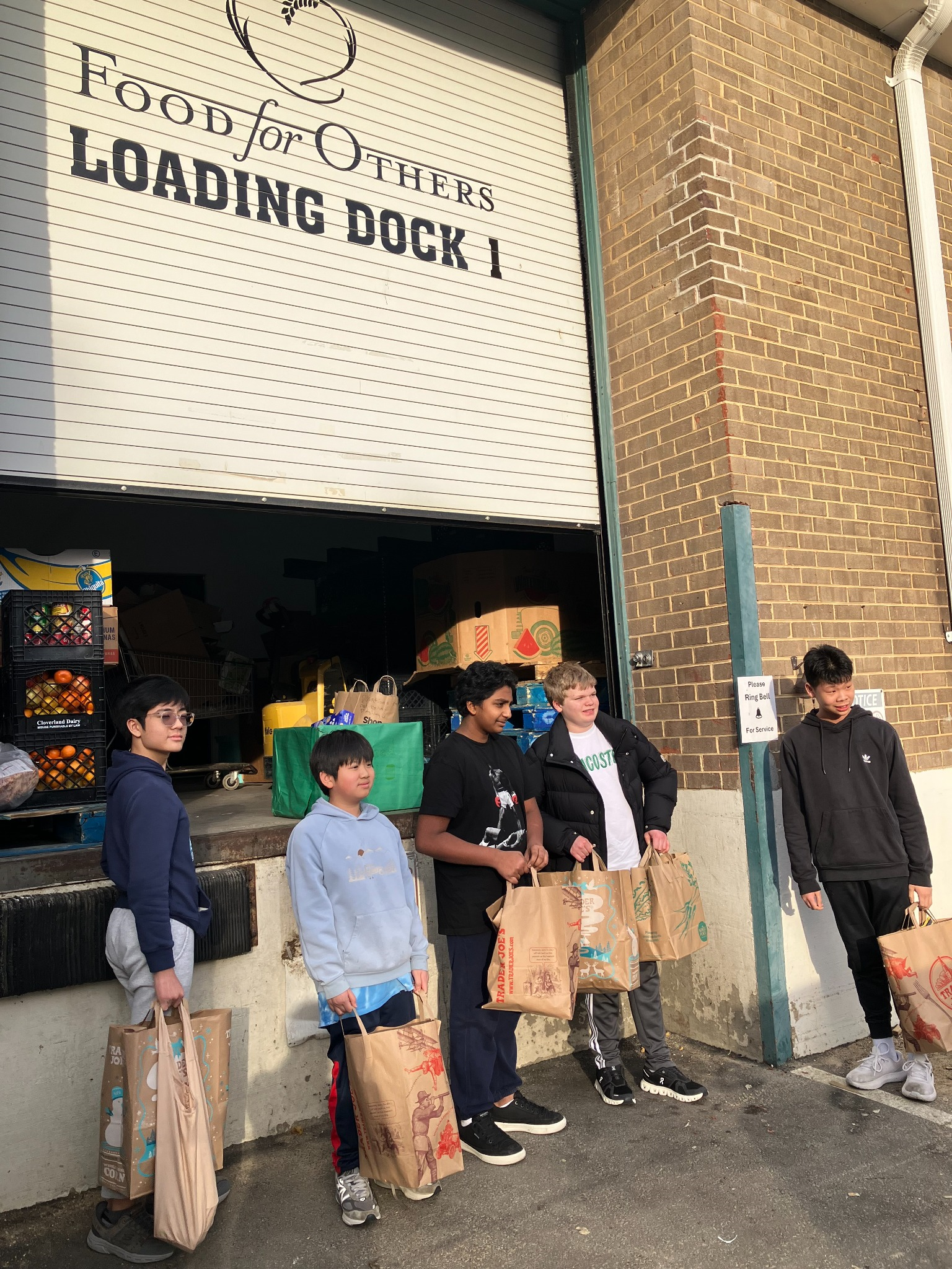 Student volunteers carrying grocery bags at a food bank